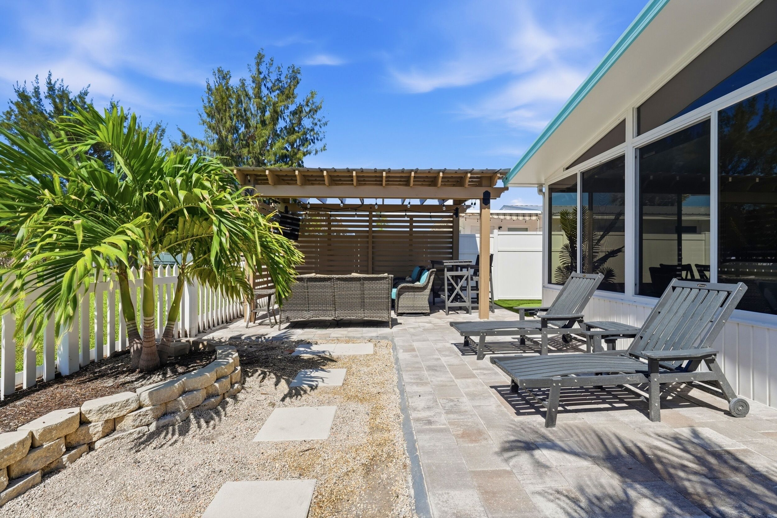 An outdoor patio with a pergola, lounge chairs, and a dining area.