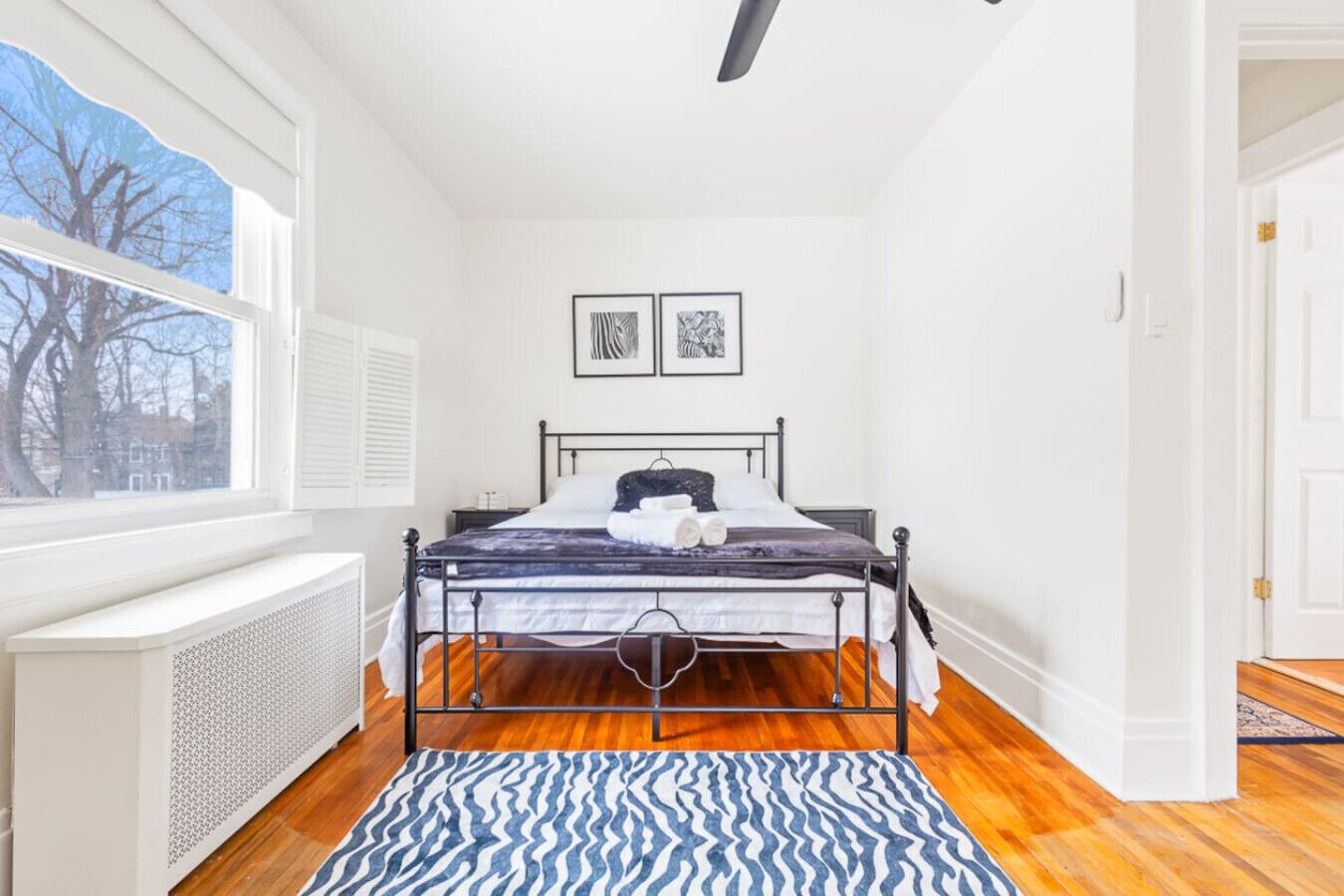 Un dormitorio con cama, un radiador, una ventana con vistas y una puerta.