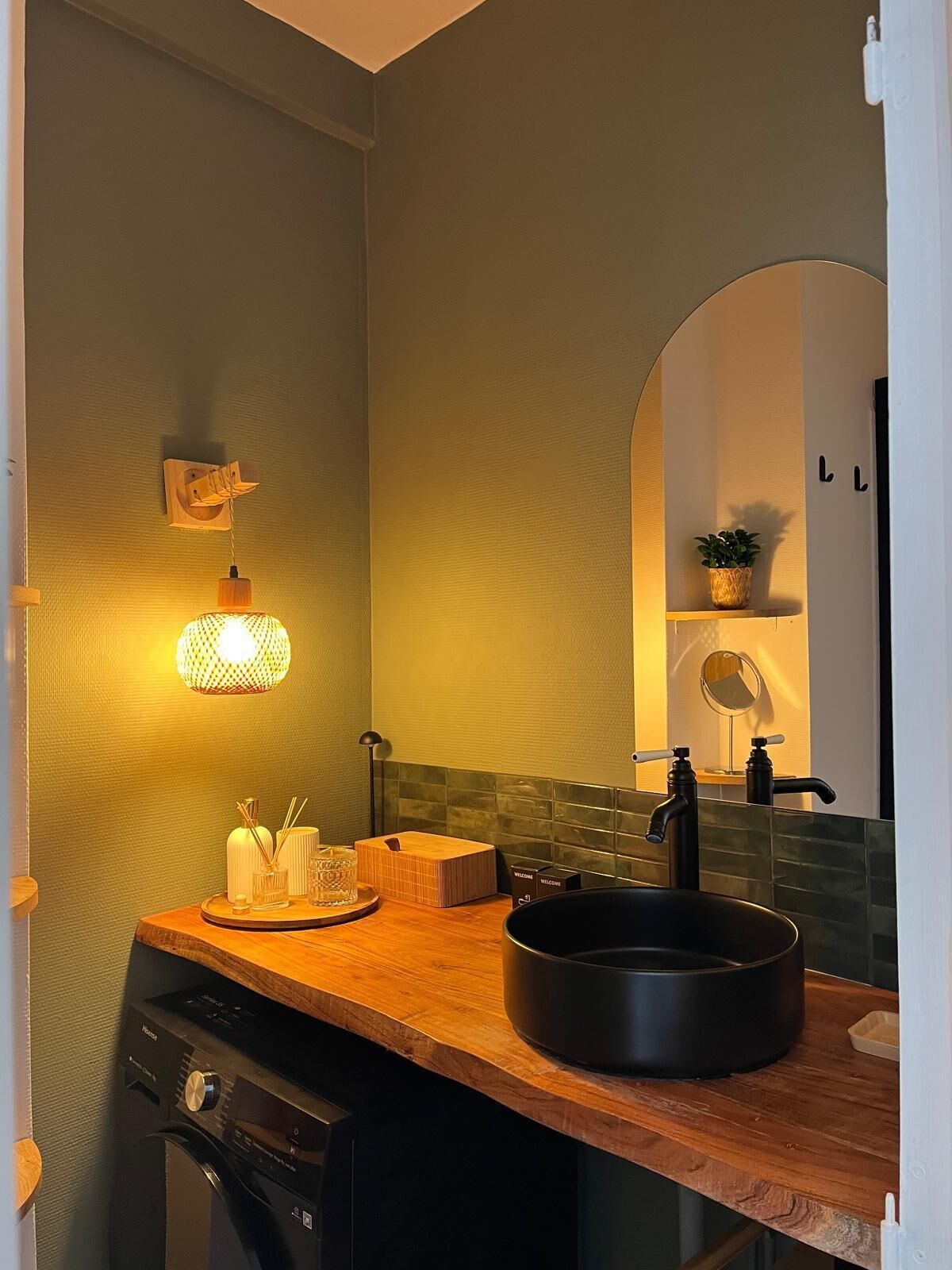 A modern bathroom with a wooden countertop, a black sink, a wall-mounted mirror, and a textured wall.