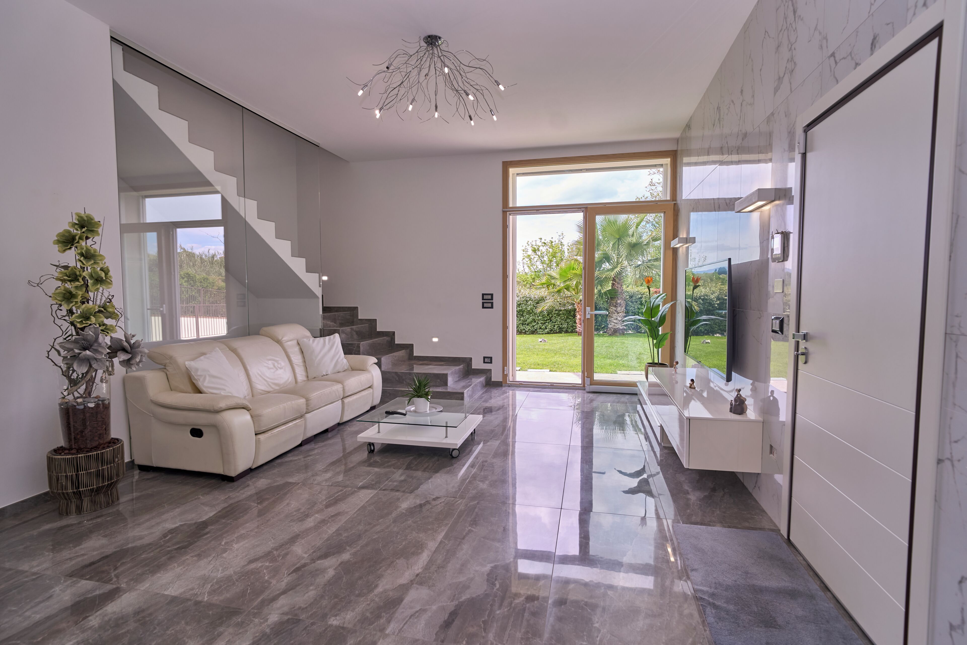 Een moderne woonkamer met een bank, salontafel en een trap naar een balkon.