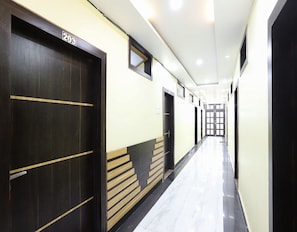 A hallway with doors marked with numbers, a tiled floor, and a light-colored wall.