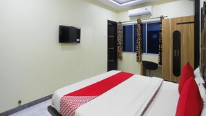 A bedroom with a bed, a TV, an air conditioner, and a wardrobe.