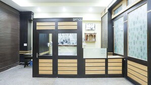 A reception area with a closed door labeled 'OFFICE,' a tiled floor, and a wall with a patterned design.