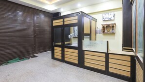 A reception area with a counter, a closed shutter door, and a wall-mounted photo display.