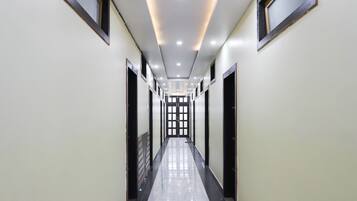 Un largo pasillo estrecho con piso brillante, puertas a ambos lados y una serie de luces en el techo.