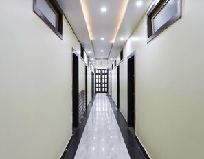 Un largo pasillo estrecho con piso brillante, puertas a ambos lados y una serie de luces en el techo.