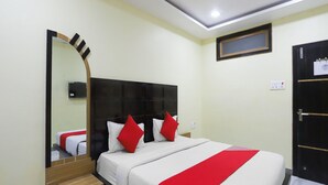 A hotel room with a bed, a wooden nightstand, a mirror, a wardrobe, and a ceiling light.