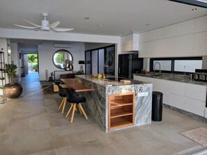 A modern kitchen with a marble island, black chairs, and a ceiling fan. - Oceanfront Villa with Private Pool, 4BR (Kralendijk)