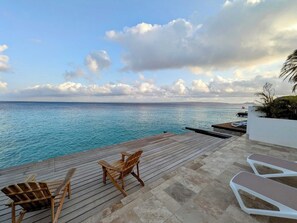 A wooden deck with lounge chairs overlooking a body of water. - Oceanfront Villa with Private Pool, 4BR (Kralendijk)