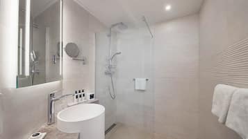 A modern bathroom with a glass-enclosed shower, a white sink, and a large mirror.