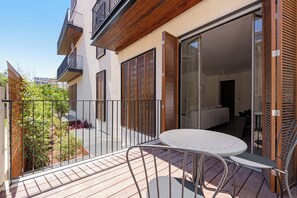 Ein Balkon mit Tisch und Stühlen, eine Schiebetür und ein Holzzaun.