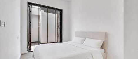 A bedroom with a bed, a wardrobe, and a door.
