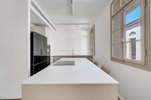 Une cuisine moderne dotée d’un grand îlot central, d’appareils électroménagers intégrés et d’une fenêtre offrant une belle vue.