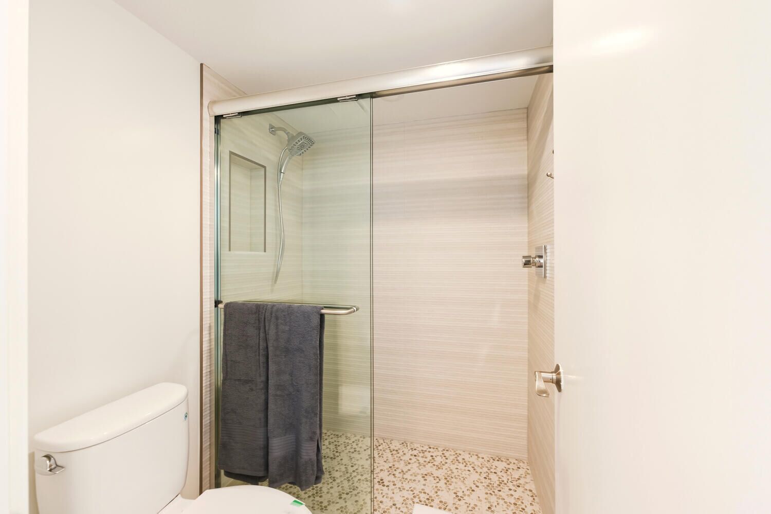 Ein Badezimmer mit Toilette, einer Duschkabine mit Glastür und einem Handtuch, das an der Tür hängt.