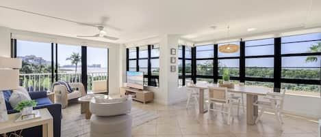 A spacious living area with a balcony, a dining area, and a TV.