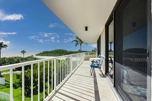 Ein Balkon mit weißer Brüstung, einem Tisch und zwei Stühlen.
