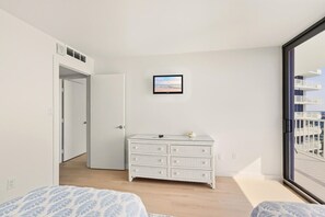 Une chambre à coucher avec un lit, une commode, un tableau encadré et un balcon avec vue.