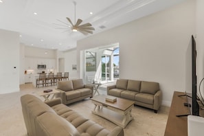 A spacious living area with a modern design, featuring a large sofa set, a coffee table, and a flat-screen TV. - Huge Waterfront Home | Six Ensuites, Pool & Spa (Marco Island)