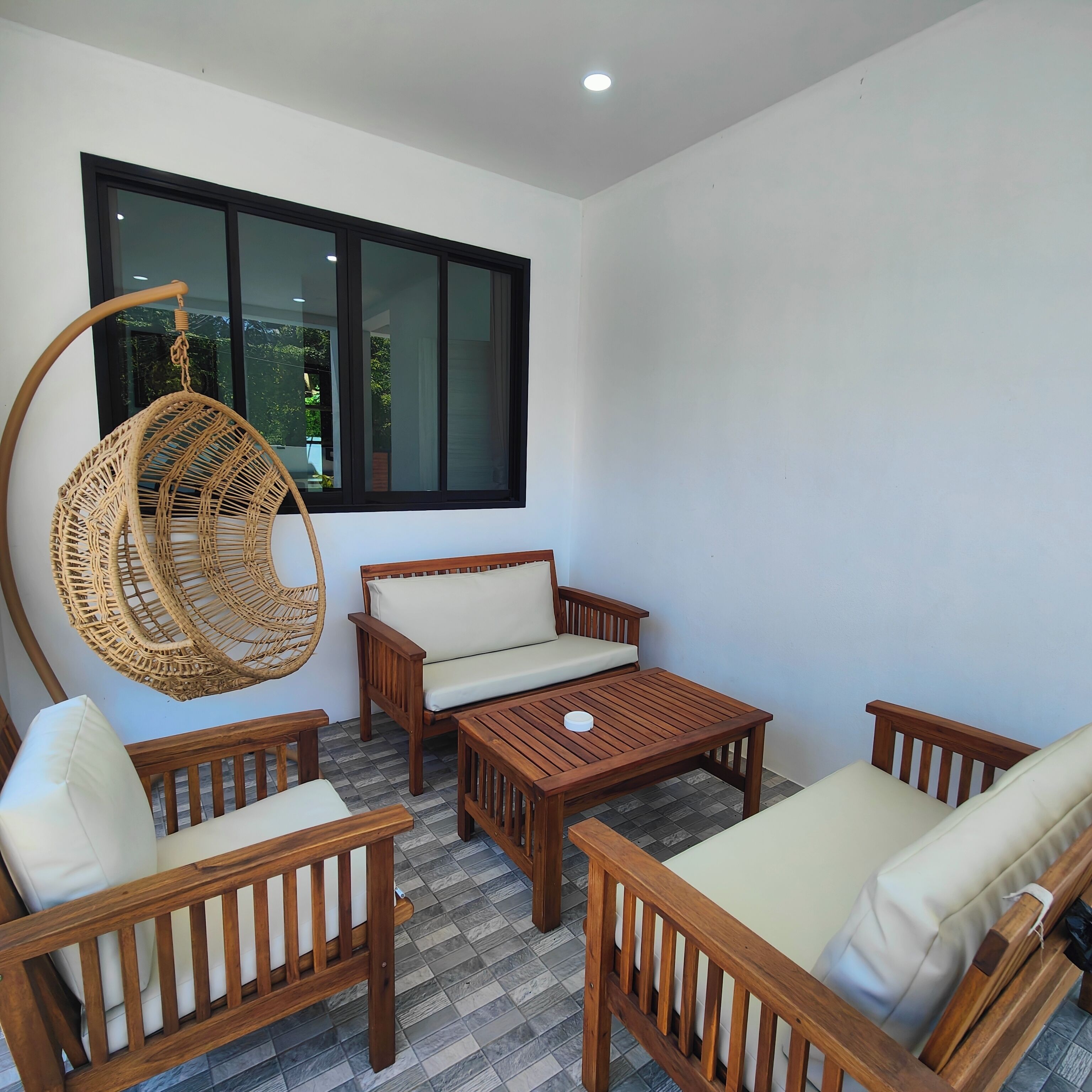 A room with a hanging chair, a sofa, and a table.