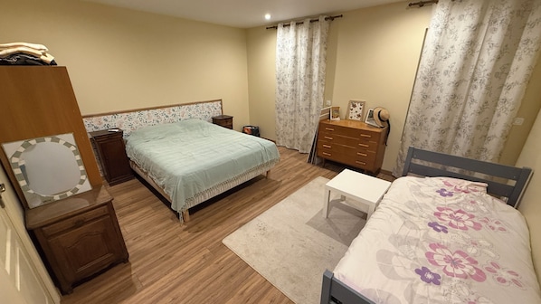A bedroom with a bed, a dresser, a bedside table, and a mirror.