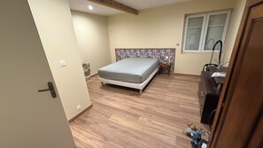 Une chambre à coucher avec un lit, une petite table, une fenêtre et une porte.