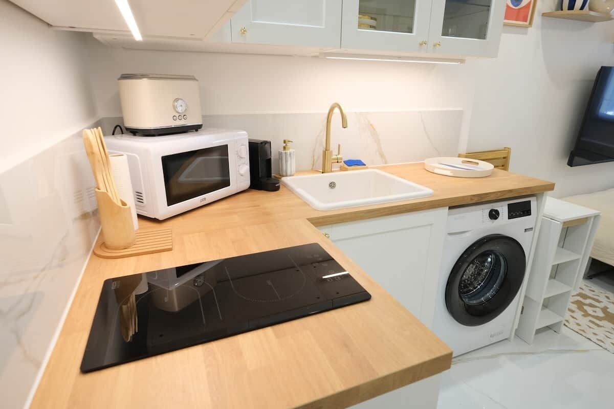 Een kleine keuken met een magnetron, broodrooster, spoelbak en wasmachine.