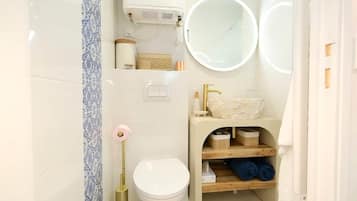 Un bagno con il water, un lavandino con specchio e un portasciugamani.