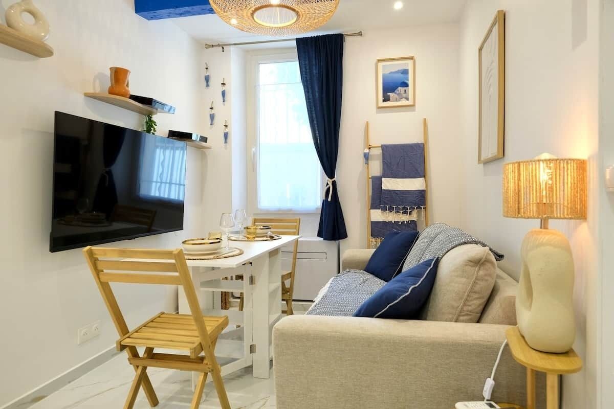 Un soggiorno moderno con televisione a schermo piatto, un tavolo da pranzo e un divano con cuscini.