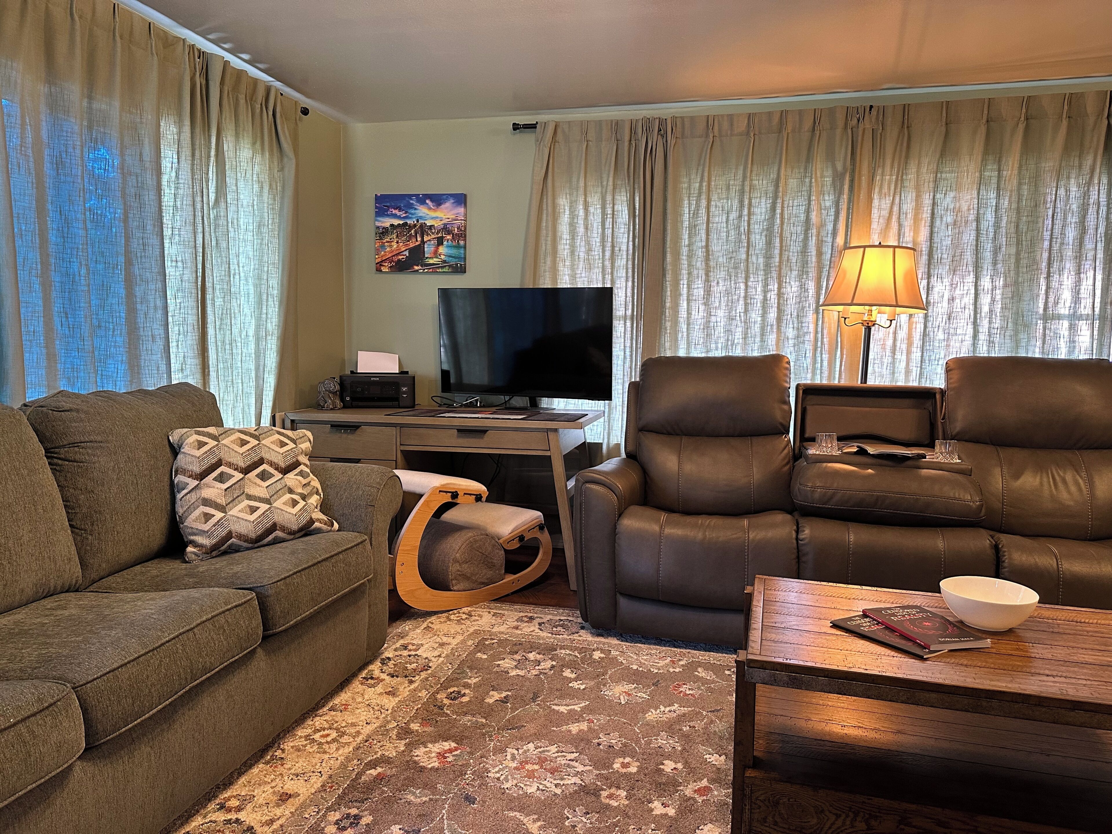 A living room with a sofa, a chair, a desk with a television, and a lamp.