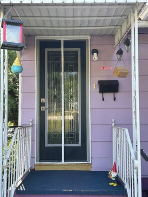 Une maison avec une porte noire, une boîte aux lettres et un panneau indiquant « PAS DE DÉMARCHEURS ».