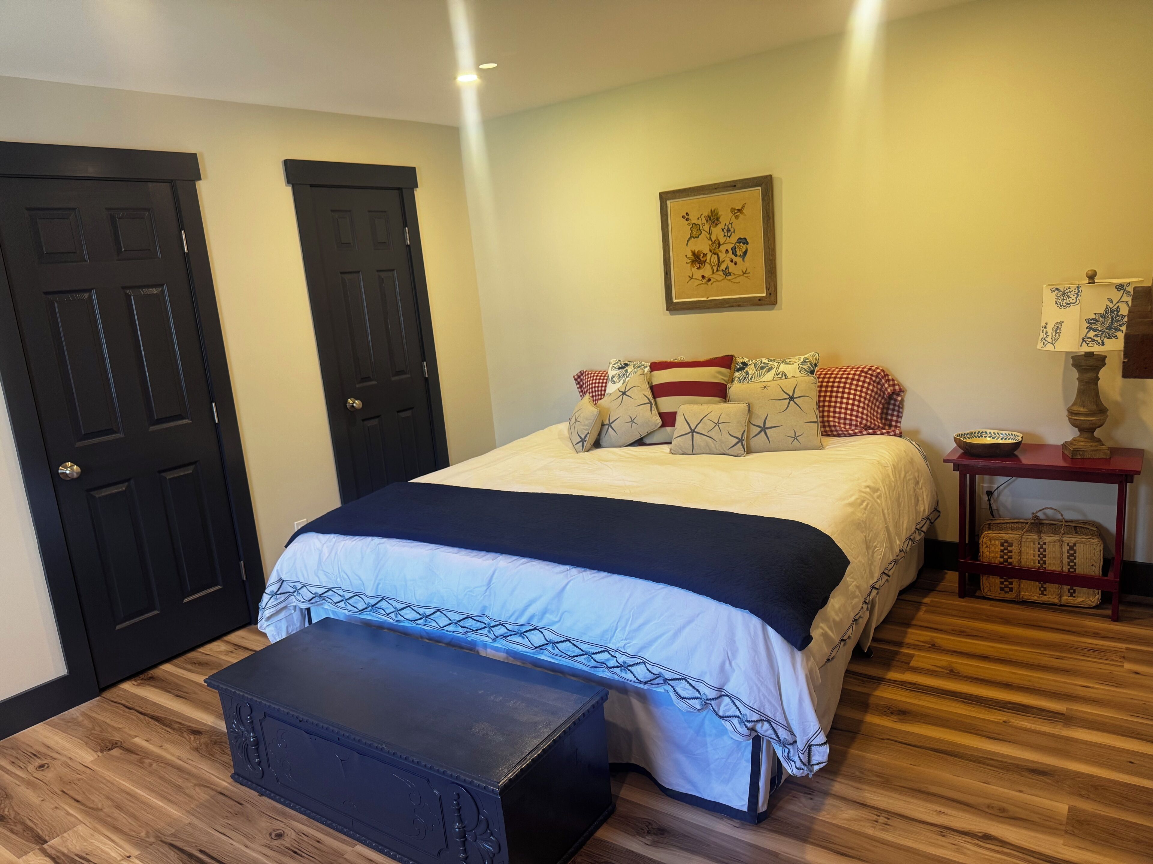 Une chambre à coucher avec un lit, une table de chevet, une lampe et une porte.