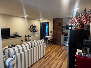 Un salon avec un canapé à rayures, un téléviseur et un coin repas comprenant une table et des chaises.