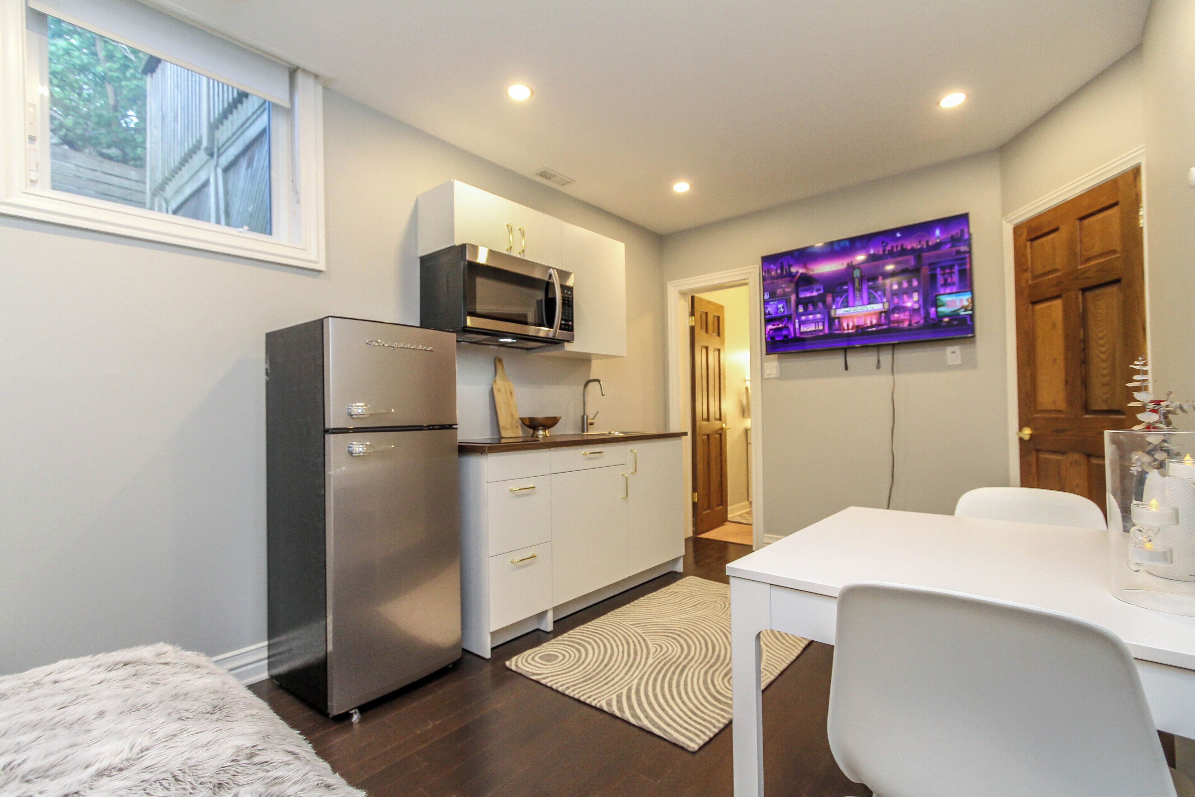 A compact kitchen with a refrigerator, microwave, and a dining area with a table and chairs.