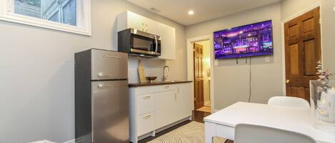 A compact kitchen with a refrigerator, microwave, and a dining area with a table and chairs.