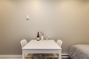 A small, white table with a wine bottle and a candle in a glass holder. - Bachelor Apartment in a perfect location of Ottawa (Ottawa)