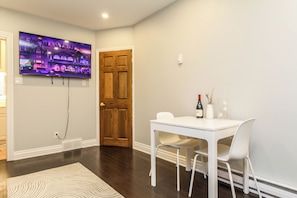 A room with a white table, two chairs, a television mounted on the wall, and a wooden door. - Bachelor Apartment in a perfect location of Ottawa (Ottawa)