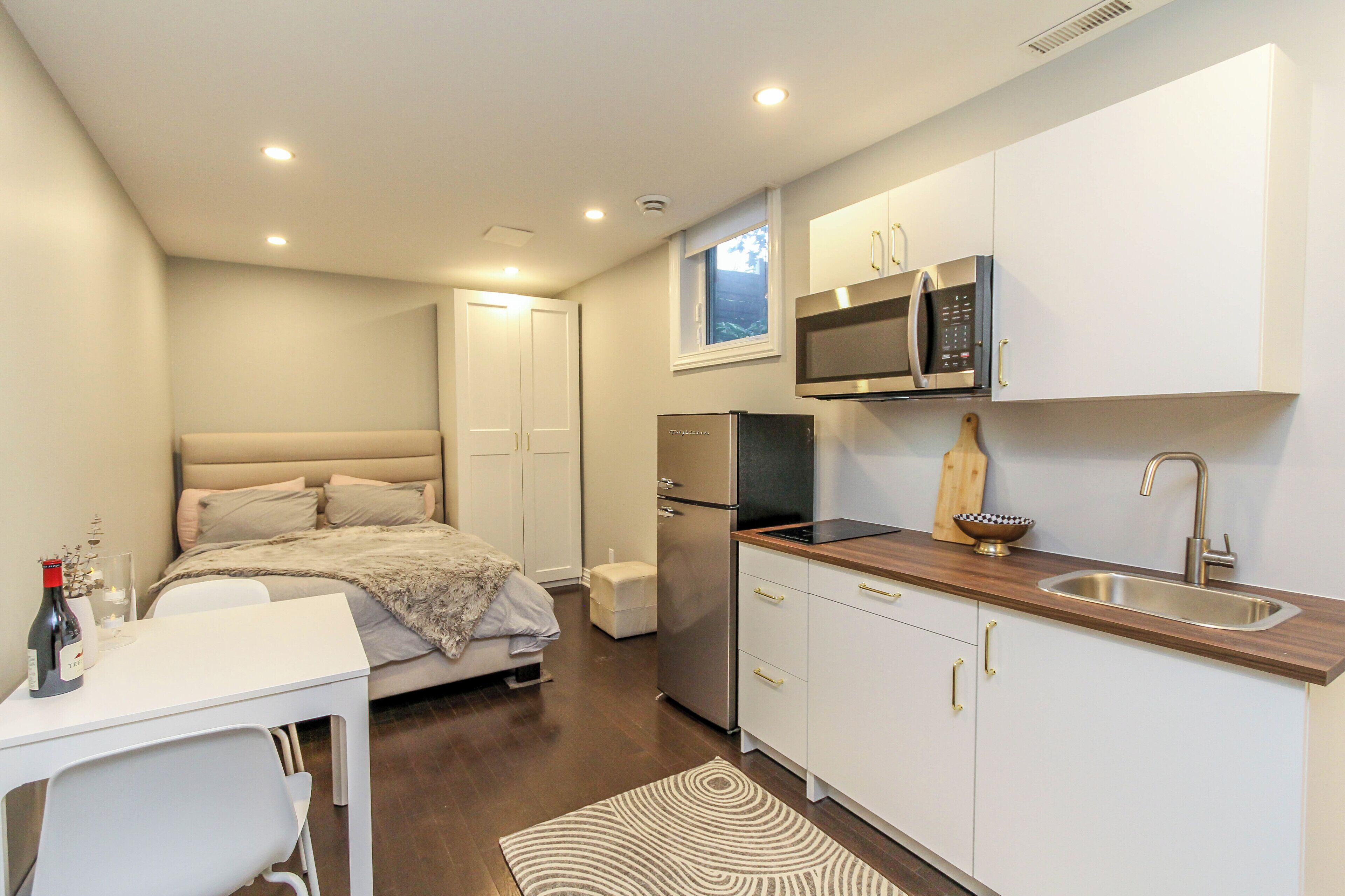 A compact kitchen with a microwave, refrigerator, and wooden countertop.