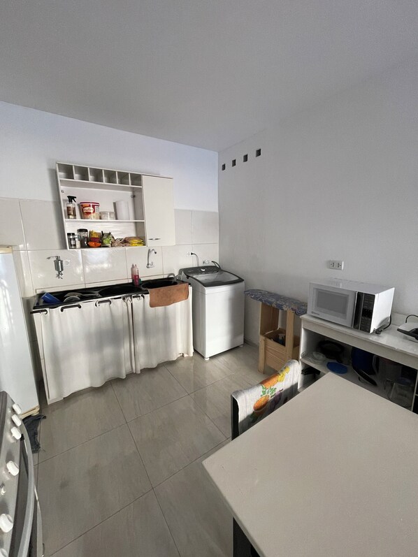 A modern kitchen with white cabinets, a microwave, and a sink.