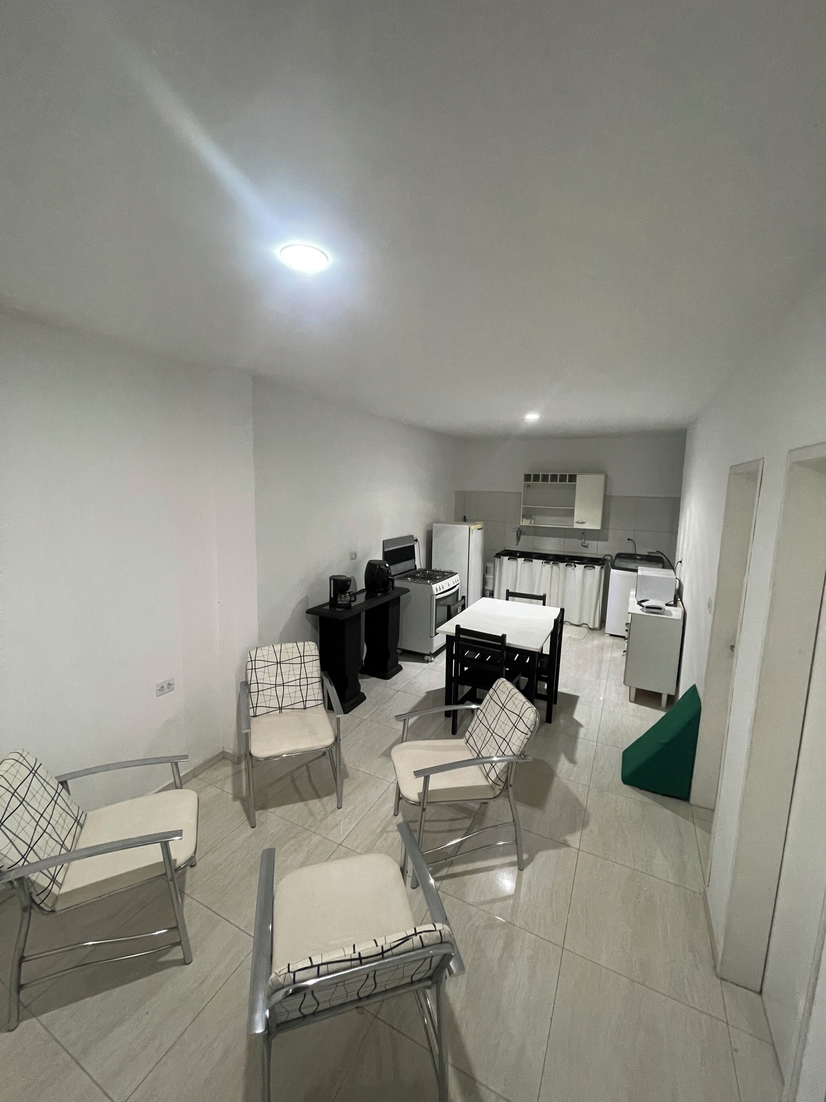 A modern kitchen with white cabinets, a dining area with a table and chairs, and a small kitchenette.