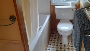 A compact bathroom with a toilet, a bathtub, and a window.