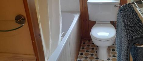 A compact bathroom with a toilet, a bathtub, and a window.