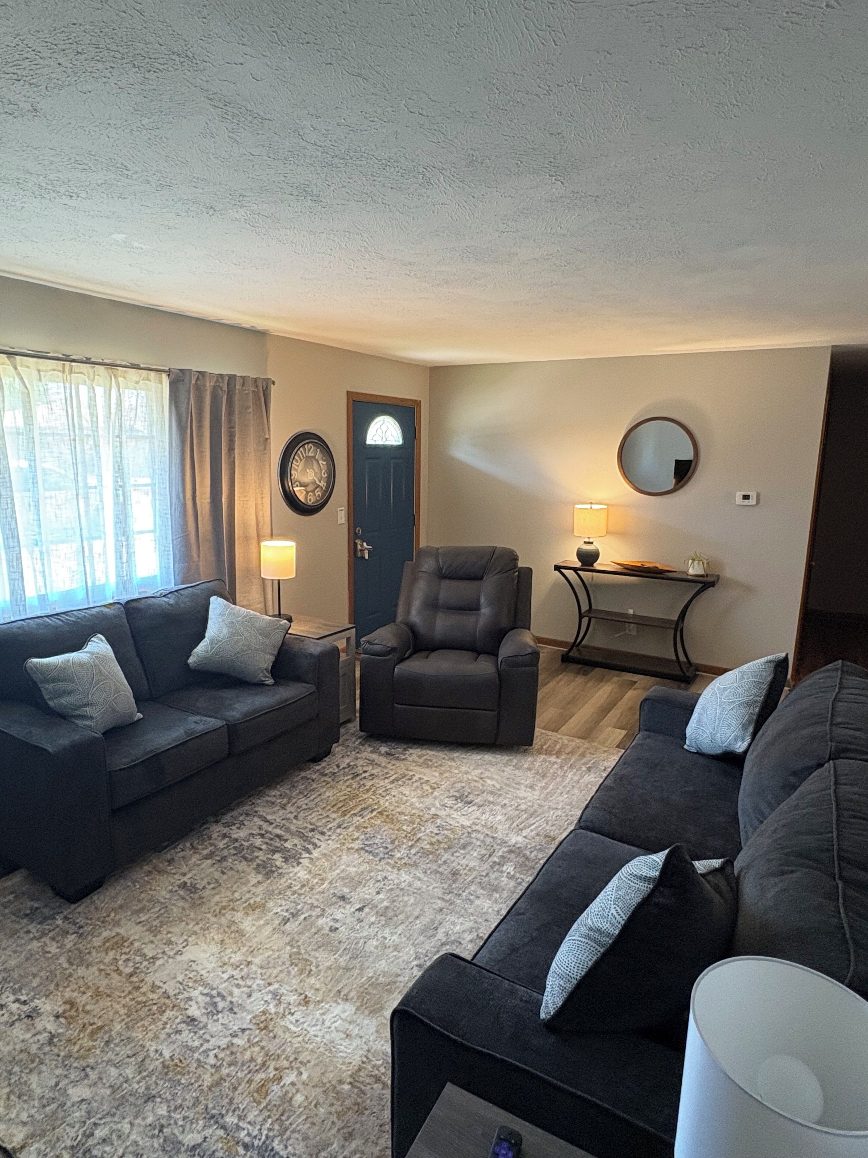 A living room with a sofa set, a chair, a coffee table, a lamp, and a door with a window.