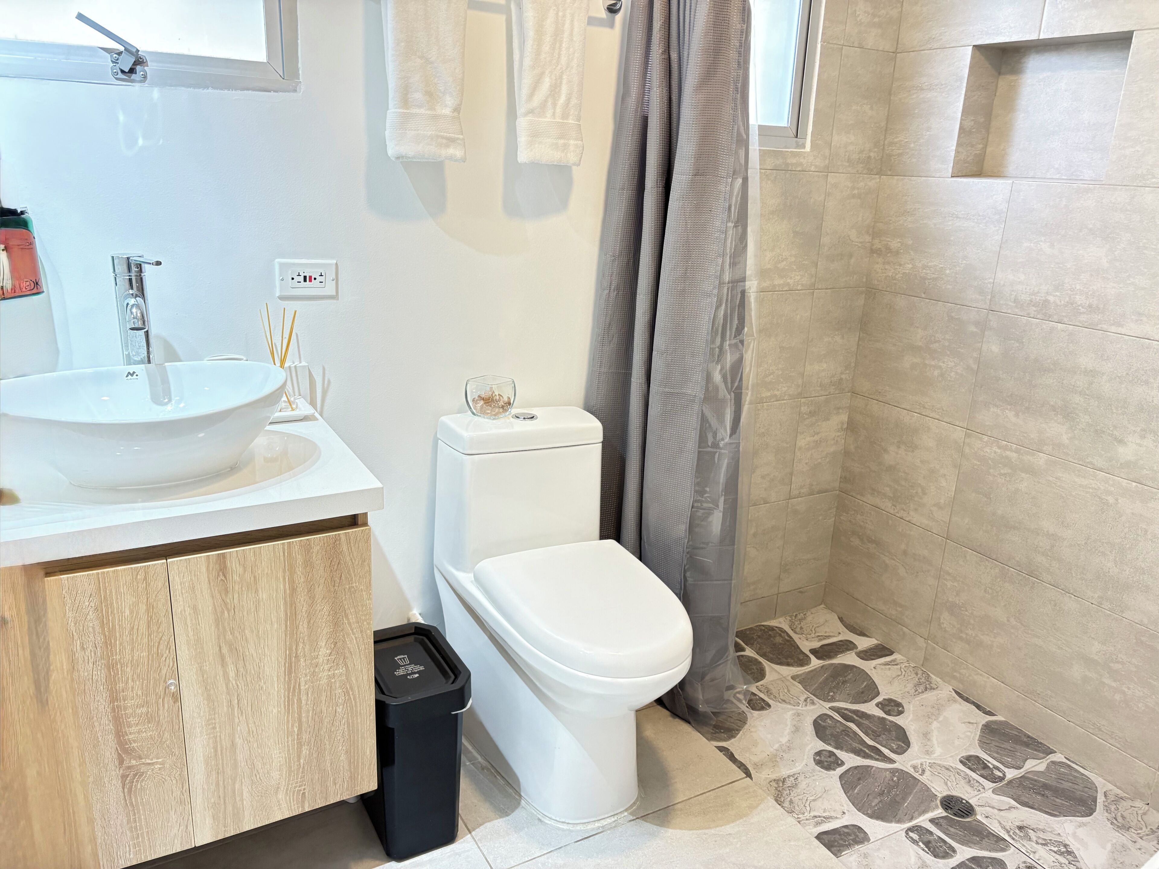 A bathroom with a white sink, toilet, and shower area.