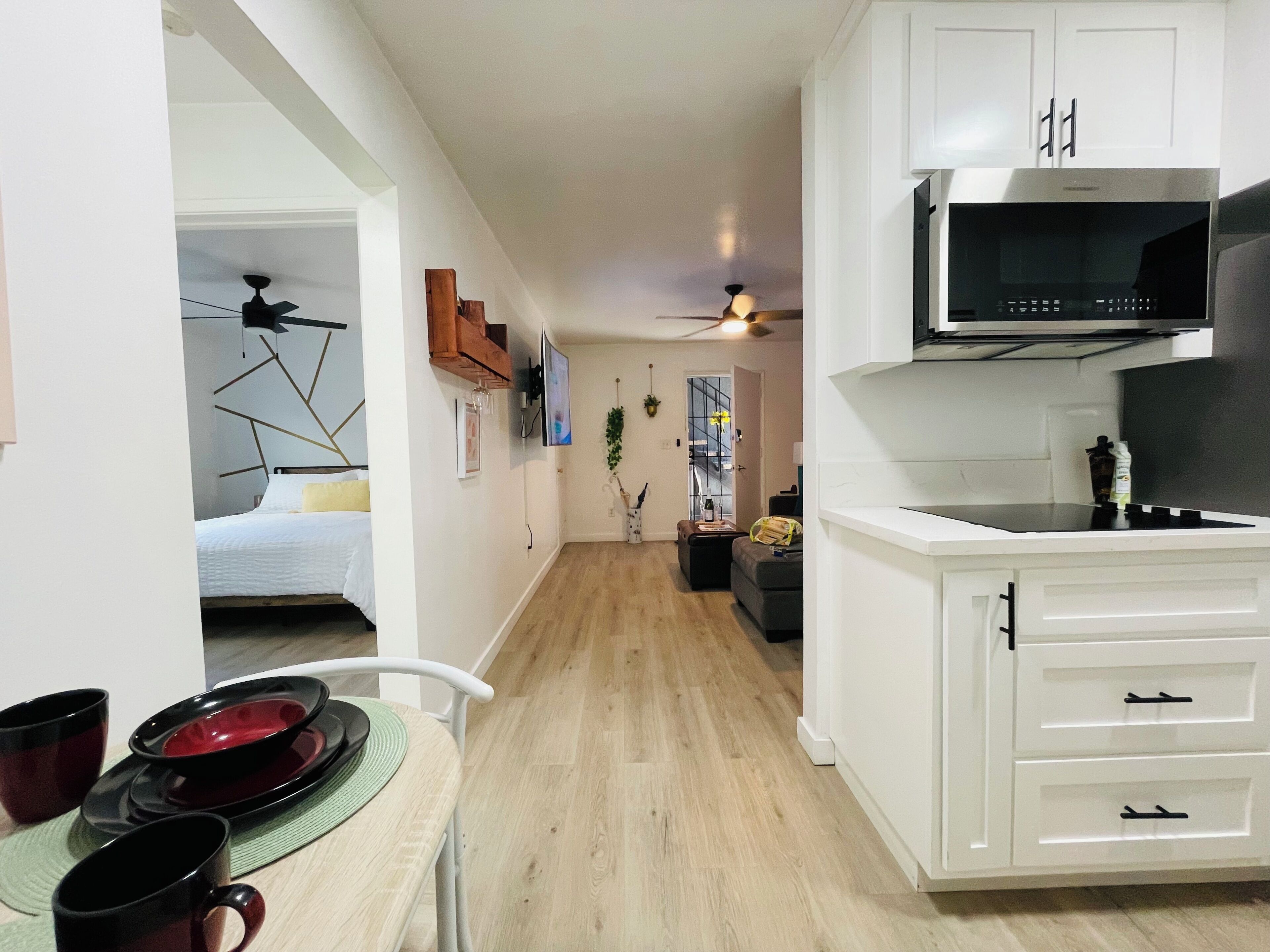 A compact kitchen with white cabinetry, a microwave, and a dining area with a table set for two.
