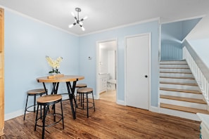 A dining area with a round table and stools, a ceiling fan, and a staircase leading to another room. - New Smyrna Beachside 2BR 3 Bath Condo Balcony (New Smyrna Beach)