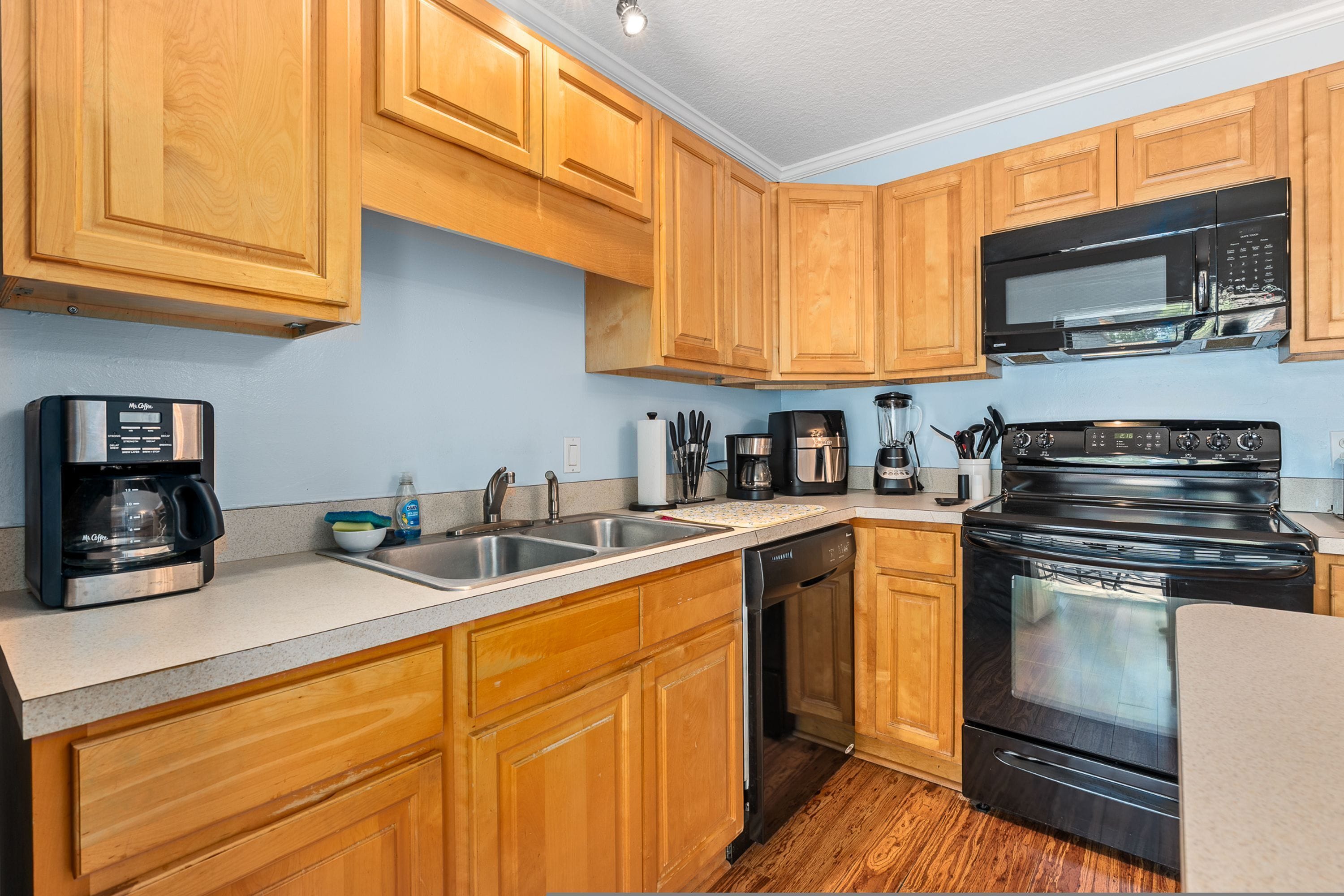 A kitchen with wooden cabinets, a stainless steel coffee maker, a microwave, and a stove.