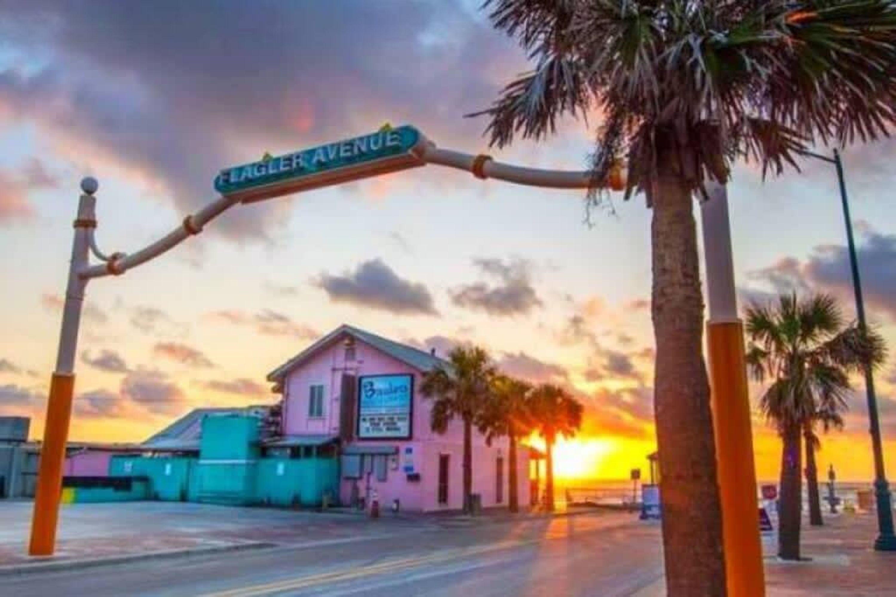 A street sign for Eagle Avenue, a building with a pink facade, and palm trees.
