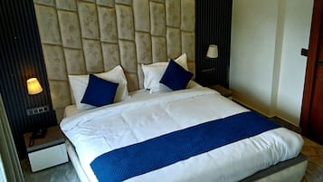 A hotel room with a large bed, a headboard, a nightstand, a lamp, and a ceiling fan.