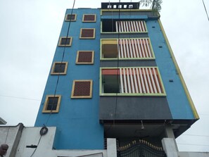 A multi-story building with a blue facade, multiple windows with shutters, and a gated entrance. - Classic Ramoji Film City (Hyderabad)
