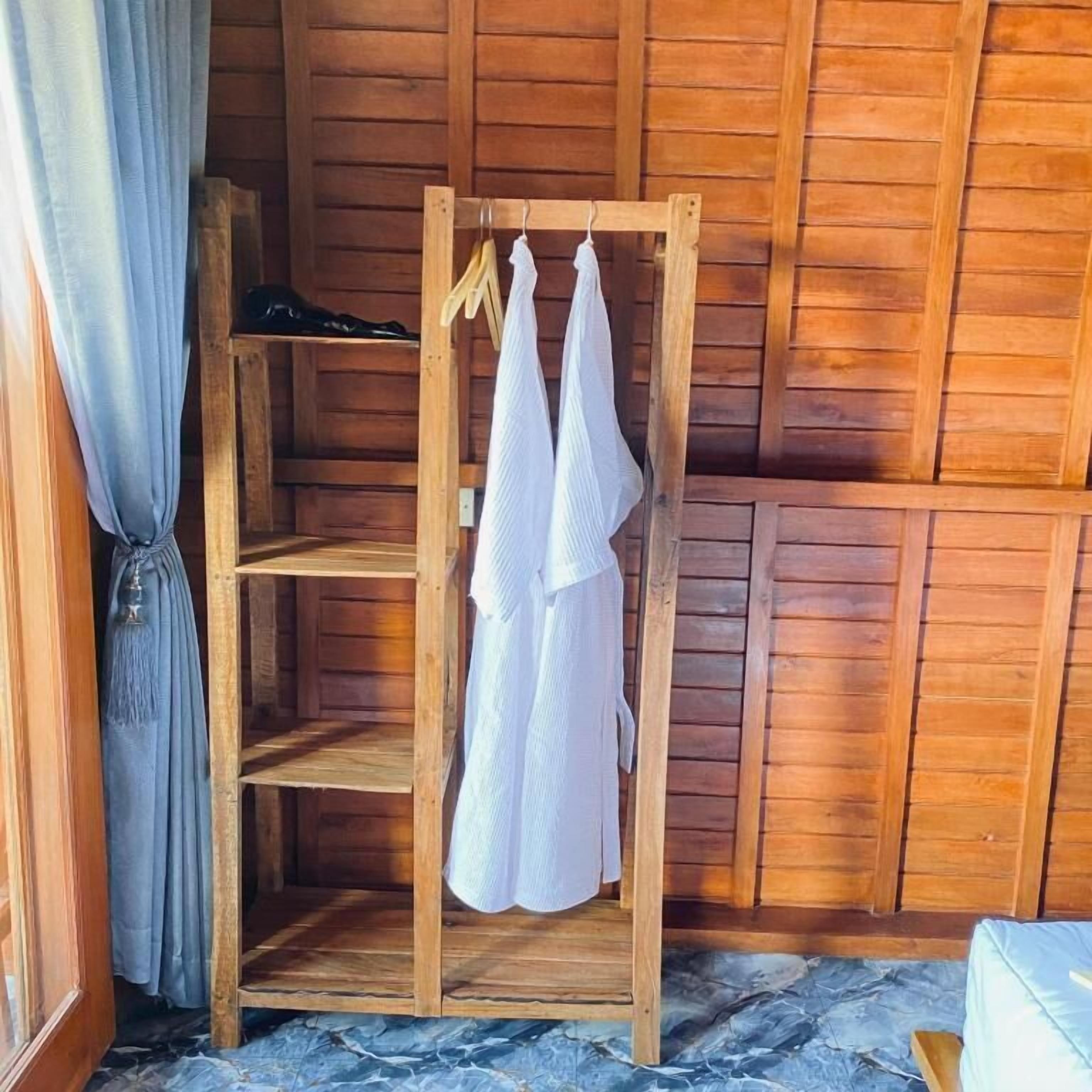 Une étagère en bois avec des vêtements suspendus et une paire de chaussures.